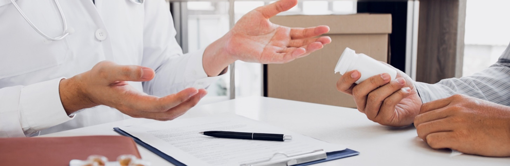 Doctor talking to a patient, who is holding a pill bottle in one hand.